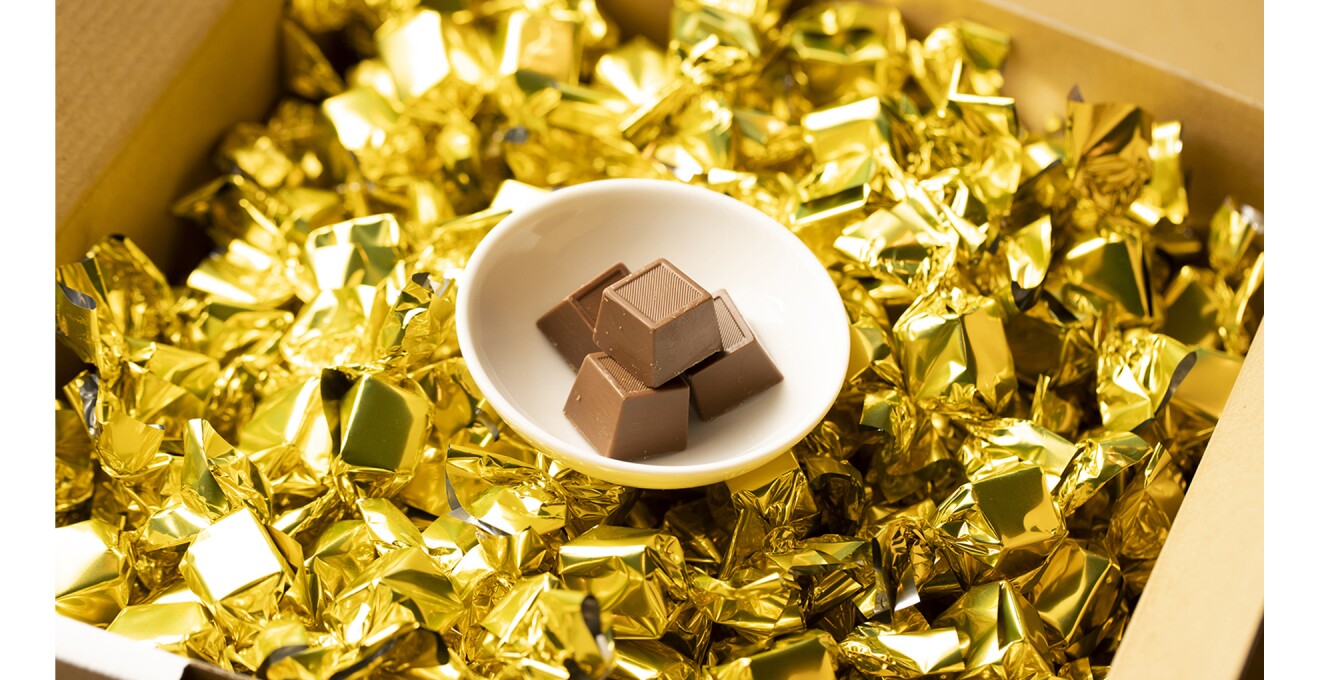 金色の包み紙に包まれた四角いチョコがダンボールいっぱいにはいっている写真