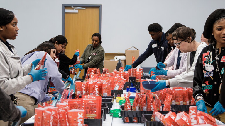 Volunteers packing food items in red bags for community service