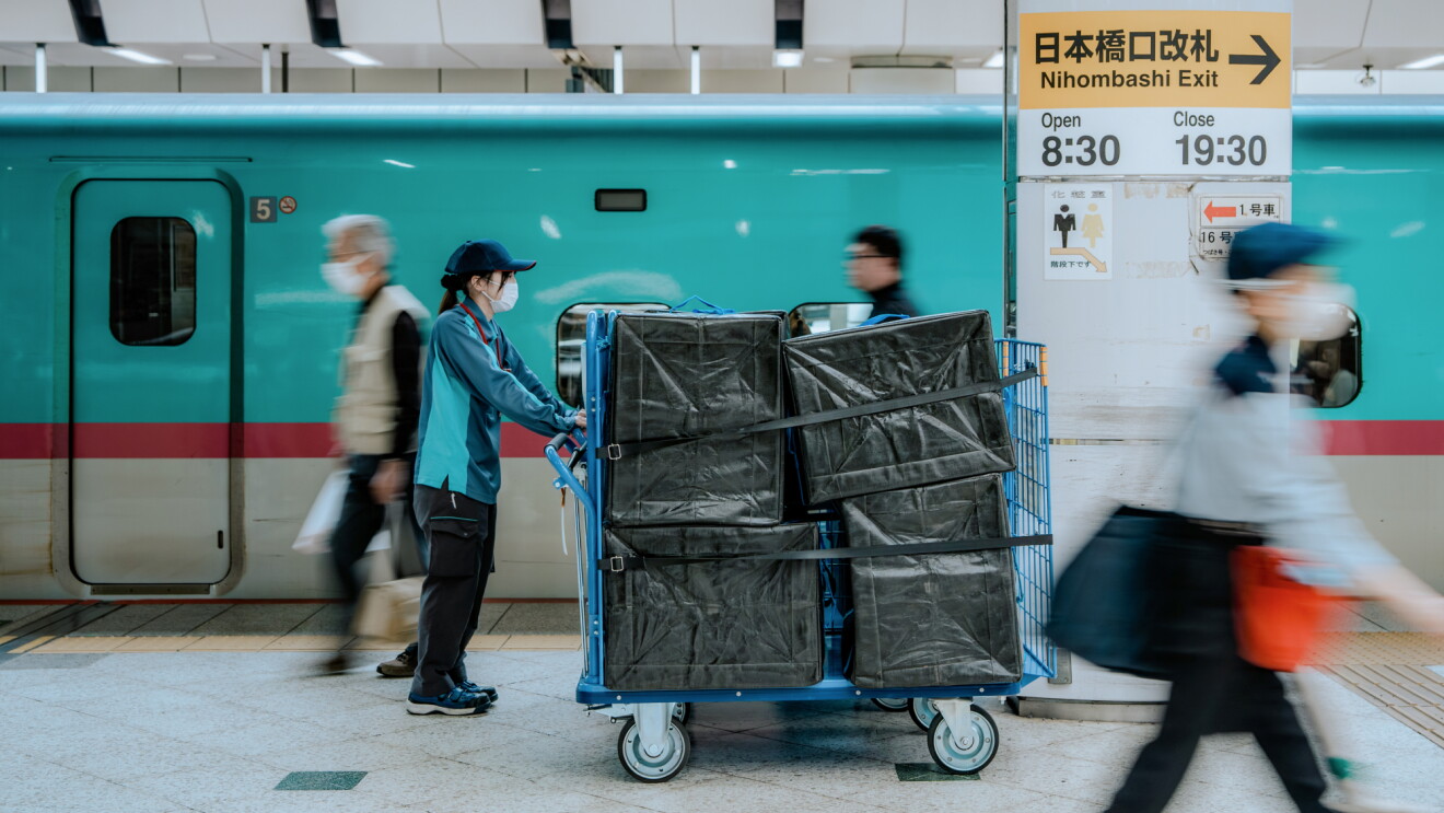 Delivery worker pushing cart of packages at Japanese train station platform