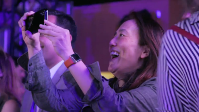 一个女人微笑着在舞台上拍摄东西的形象。