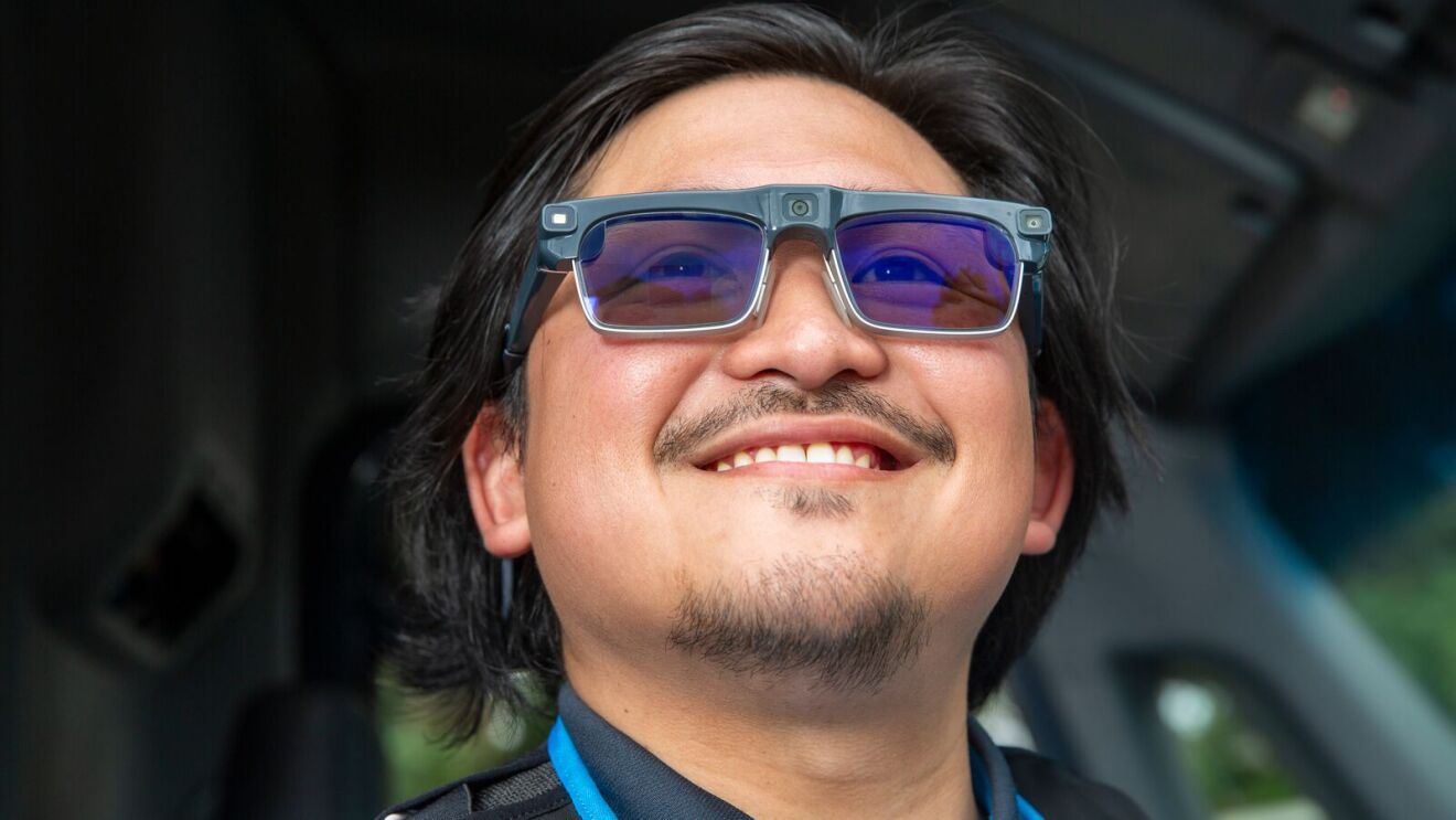 Smiling man wearing high-tech smart glasses with blue-tinted lenses