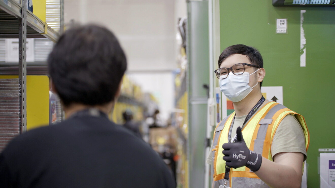 A man wearing a mask can be seen giving a thumbs up to his colleague
