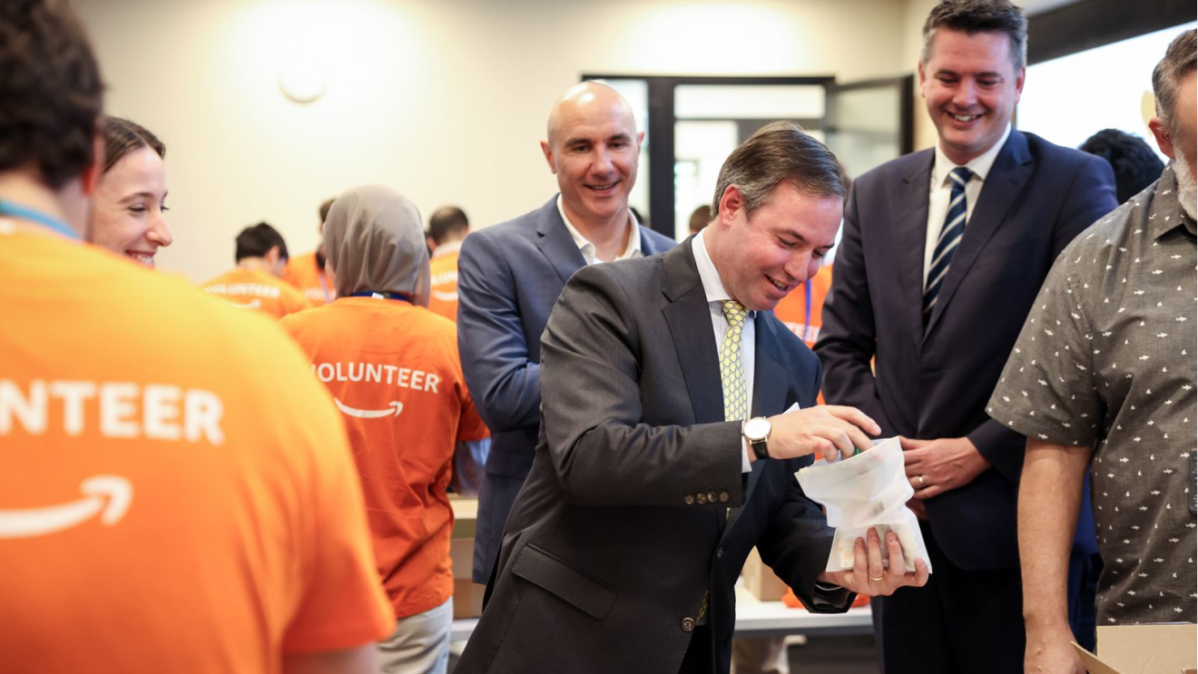 Royal Highness Prince Guillaume, Hereditary Grand Duke of Luxembourg, and Minister of Economy Lex Delles interact with volunteers in bright orange shirts at community event in Luxembourg