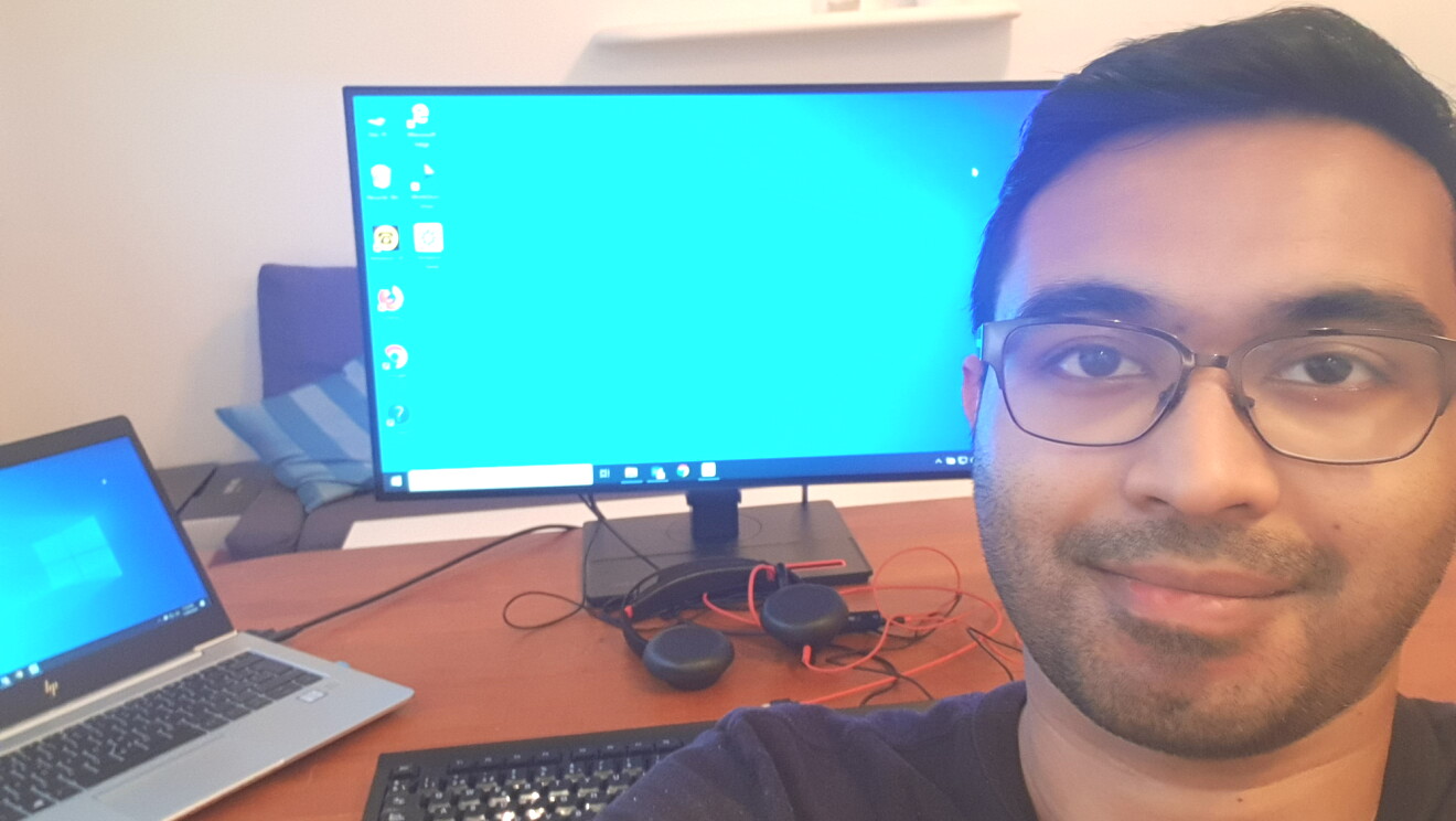 Selfie photo of a man sitting in front of a desk with a computer on it.