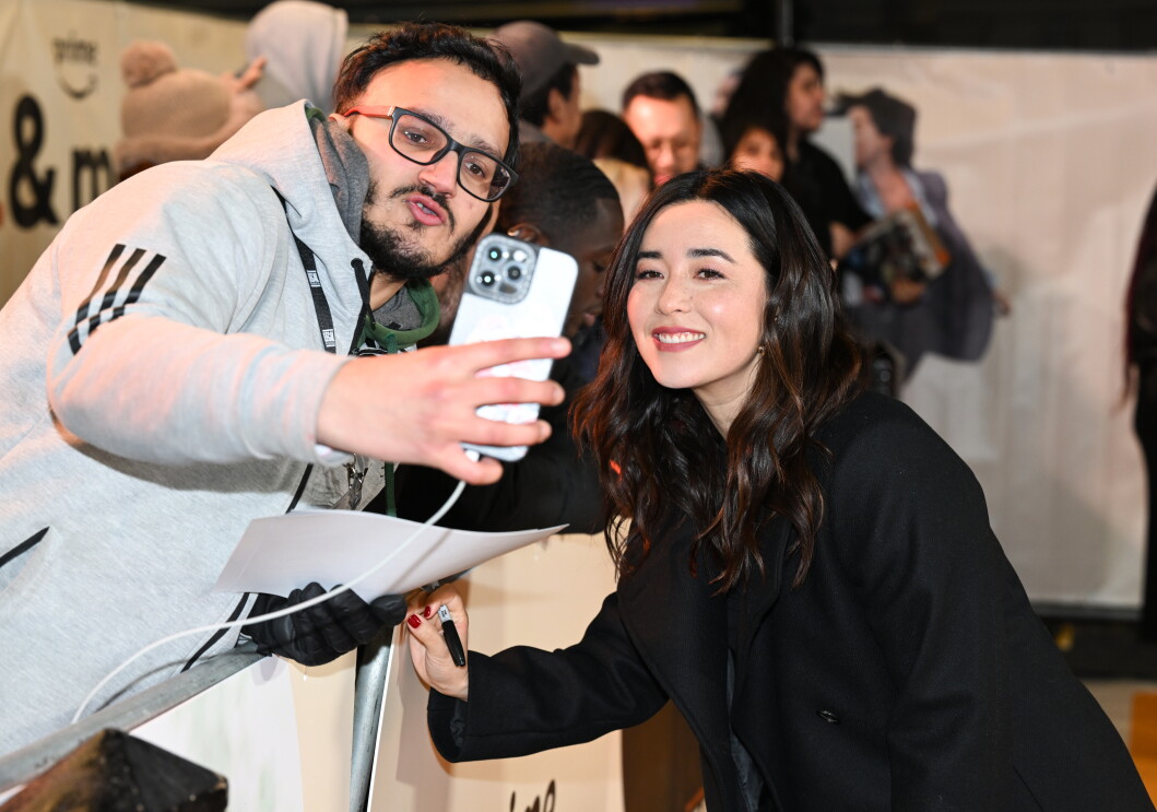 Maya Erskine smiling taking a picture with a fan