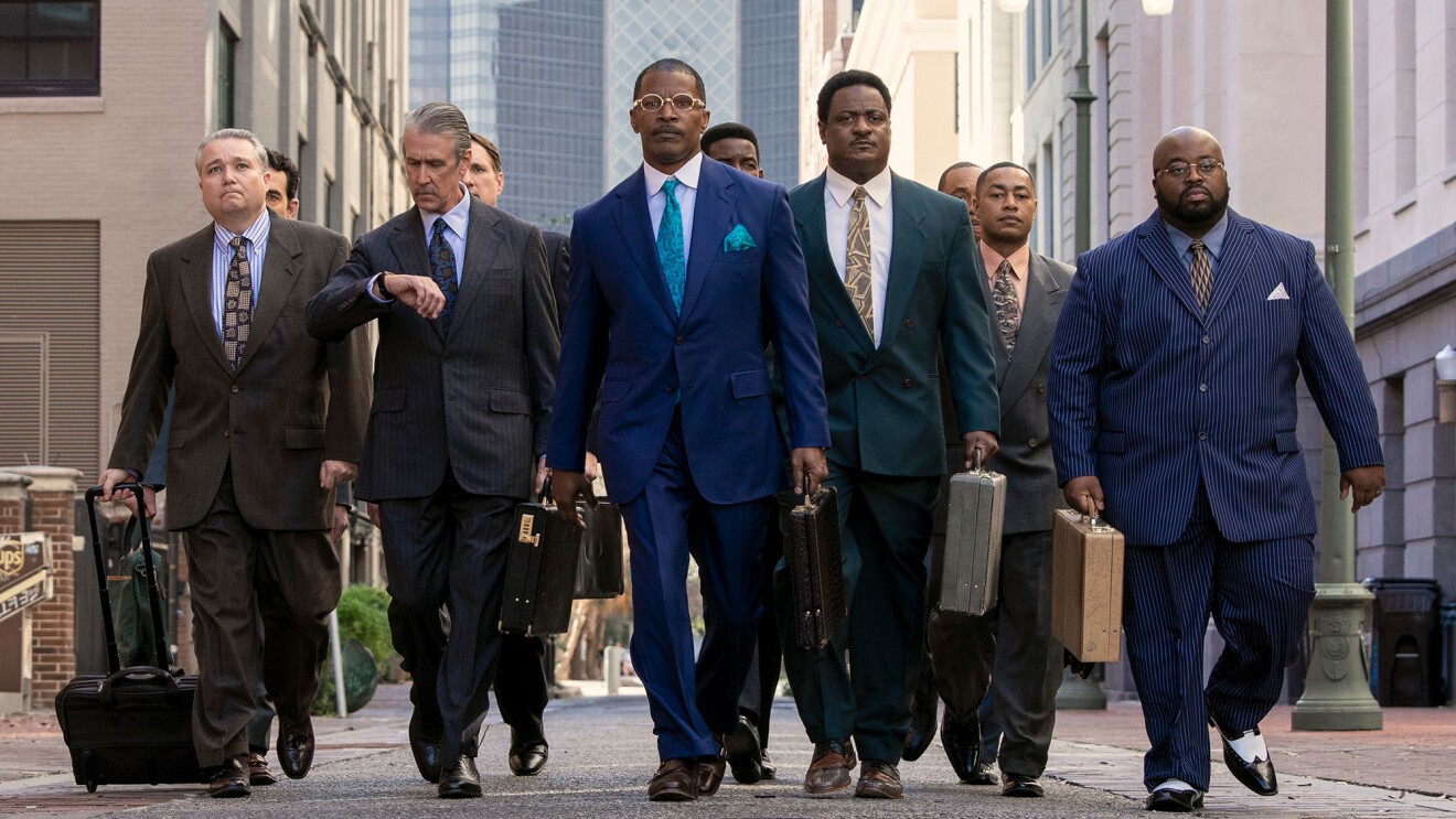 A group of men, led by Jamie Foxx, walking down the street in the movie The Burial. 