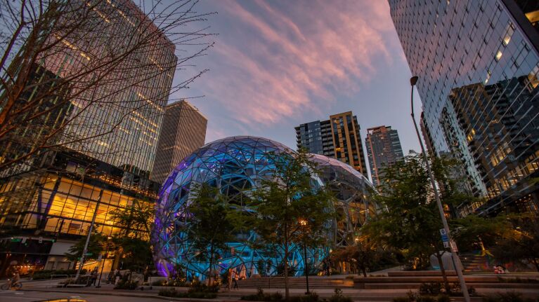 Amazon Spheres glowing at dusk amid Seattle's downtown skyline