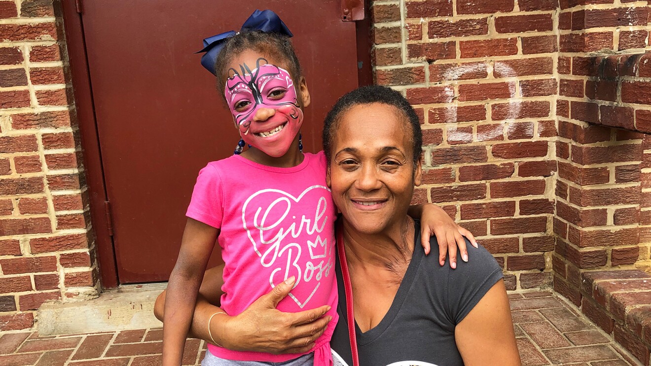 A photo of a little girl and older woman hugging in front of an apartment in Washington, D.C. 