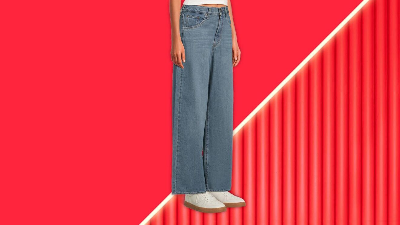 Wide-leg jeans on model against red background with diagonal line