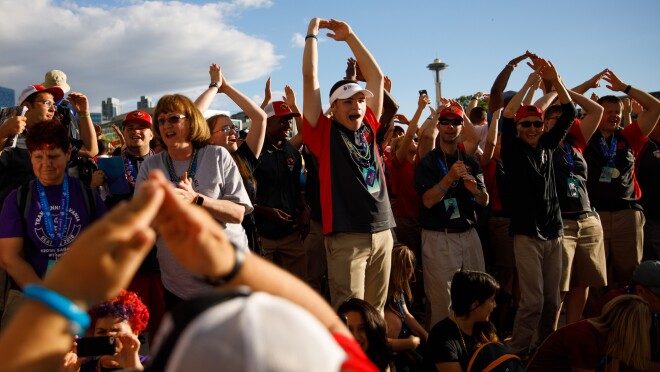 2018年美国特奥会运动员在闭幕式上欢呼。许多名运动员正拿着他们的手臂,上面的头,用手指触摸。其他的人鼓掌。