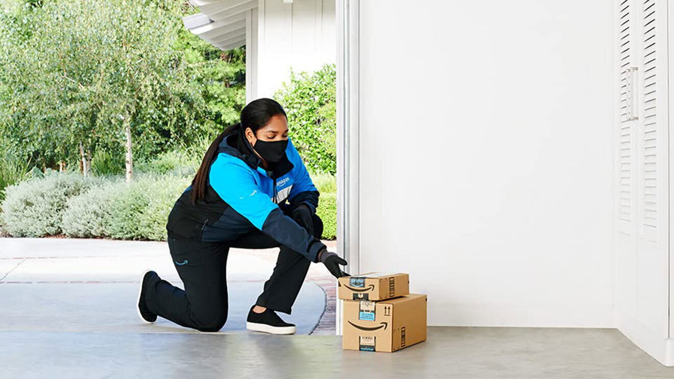 An Amazon employee delivering a package inside a garage. 