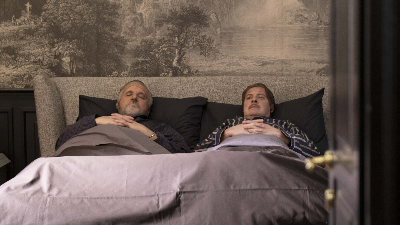 Christian De Sica e Pietro Sermonti distesi su un divano letto in una scena della serie Gigolò per caso