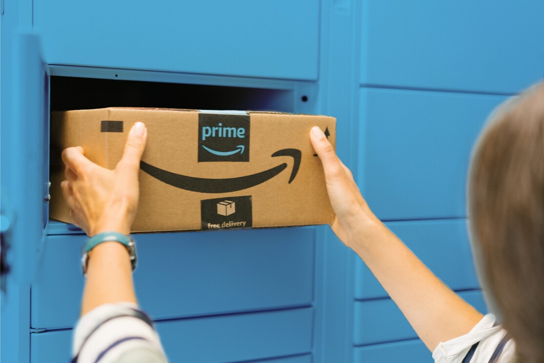 Man sieht 2 Hände, die aus einem blauen Amazon Locker ein Amazon Päckchen entnehmen.