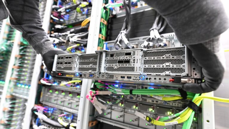A data center technician holding a server rack