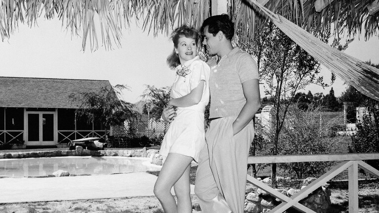 A black and white image from Amy Poehler’s documentary "Lucy and Desi" of two people posing while looking at each other in an outdoor setting.