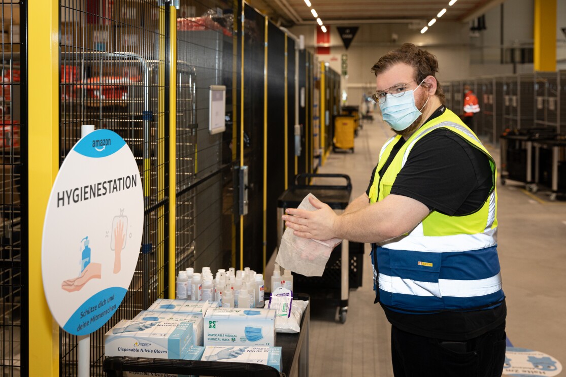 Ein Mitarbeiter an der Hygienestation beim Desinfizieren der Hände.