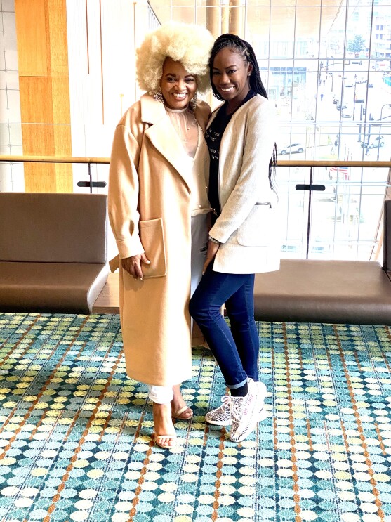 An image of two women smiling for a photo at a conference.