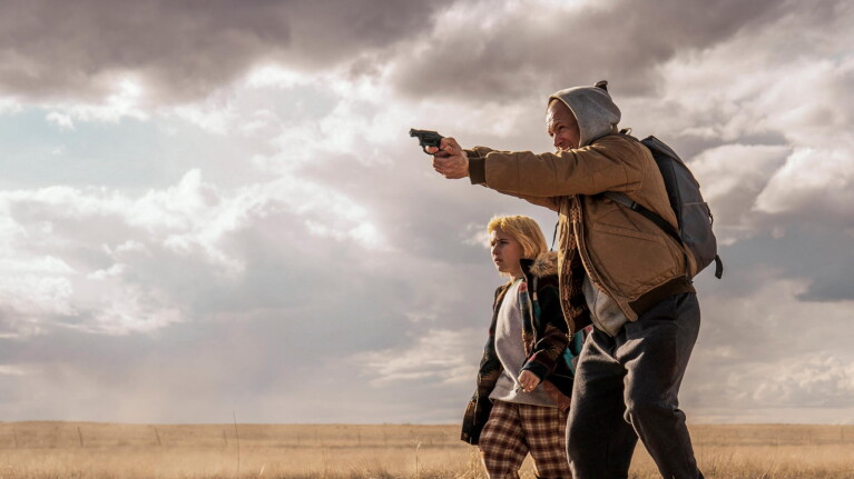 Ana Sophia Heger and Taron Egerton together pointing a gun 