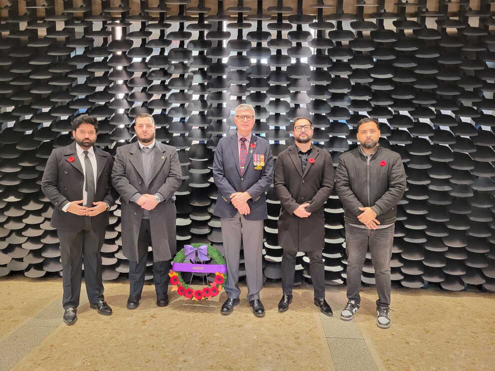 Un groupe d'hommes portant des coquelicots, debout près d'une couronne.