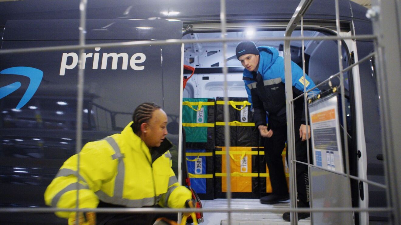 Amazon employees loading packages into a delivery van.