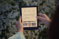 Mains tenant une liseuse Kindle affichant une interface en français sur fond de marguerites