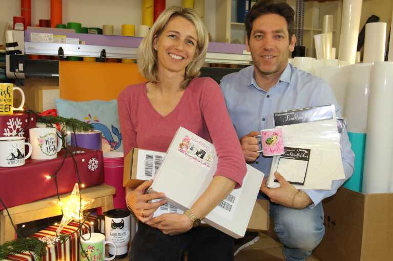 Amazon_Weihnachten 2018_Wandtattoo Loft-Mitarbeiter stehen im Laden und präsentieren ihre Produkte.