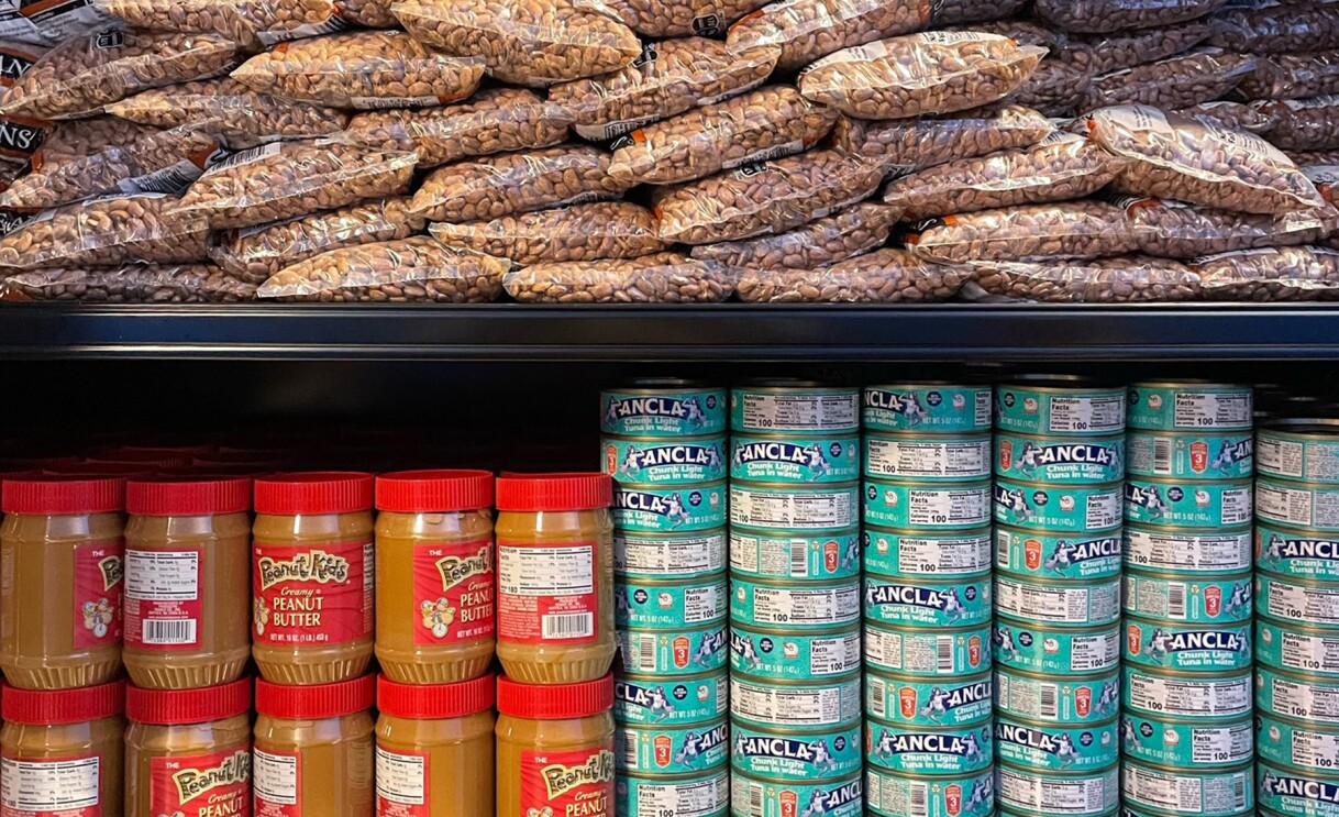An image of a food pantry full off assorted food items including beans, peanut butter and tuna in water.