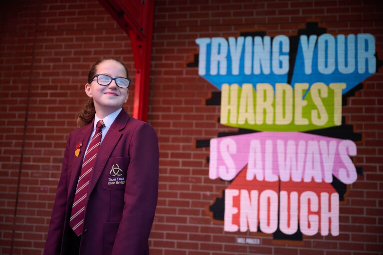A student stands in front of a Will Poulter quote