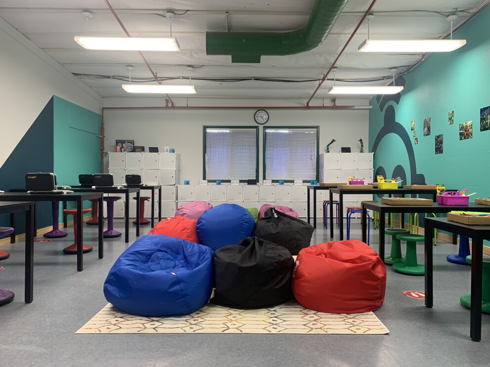 An image of a classroom with learning stations, bean bag chairs, cubbies, and other learning tools.