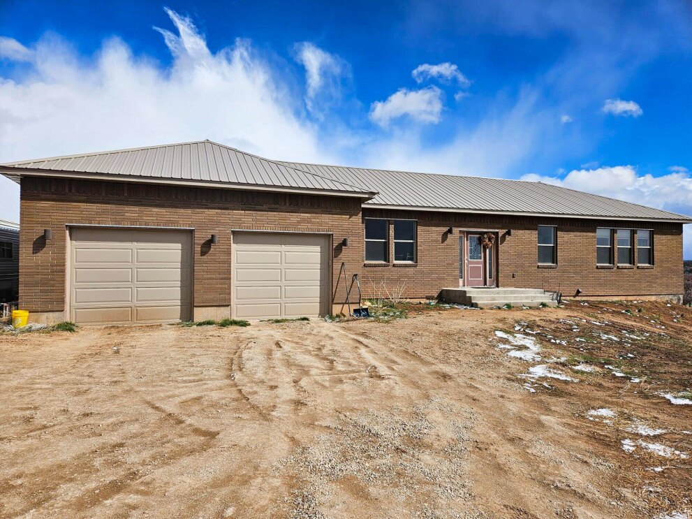 An image of a tan brick home with a large garage. There is a beautiful blue sky above the home.