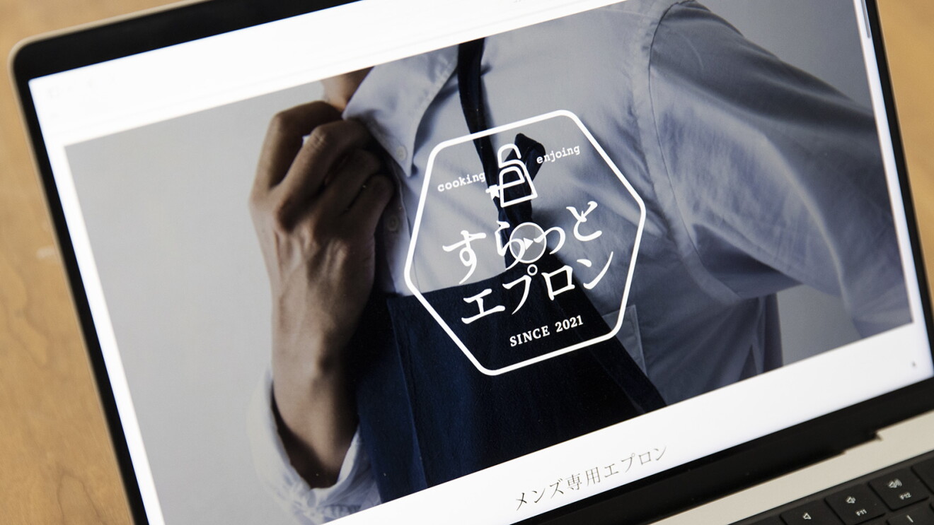 PCの画面　シャツを着た男性の写真の上に六角形のすらっとエプロンのロゴ