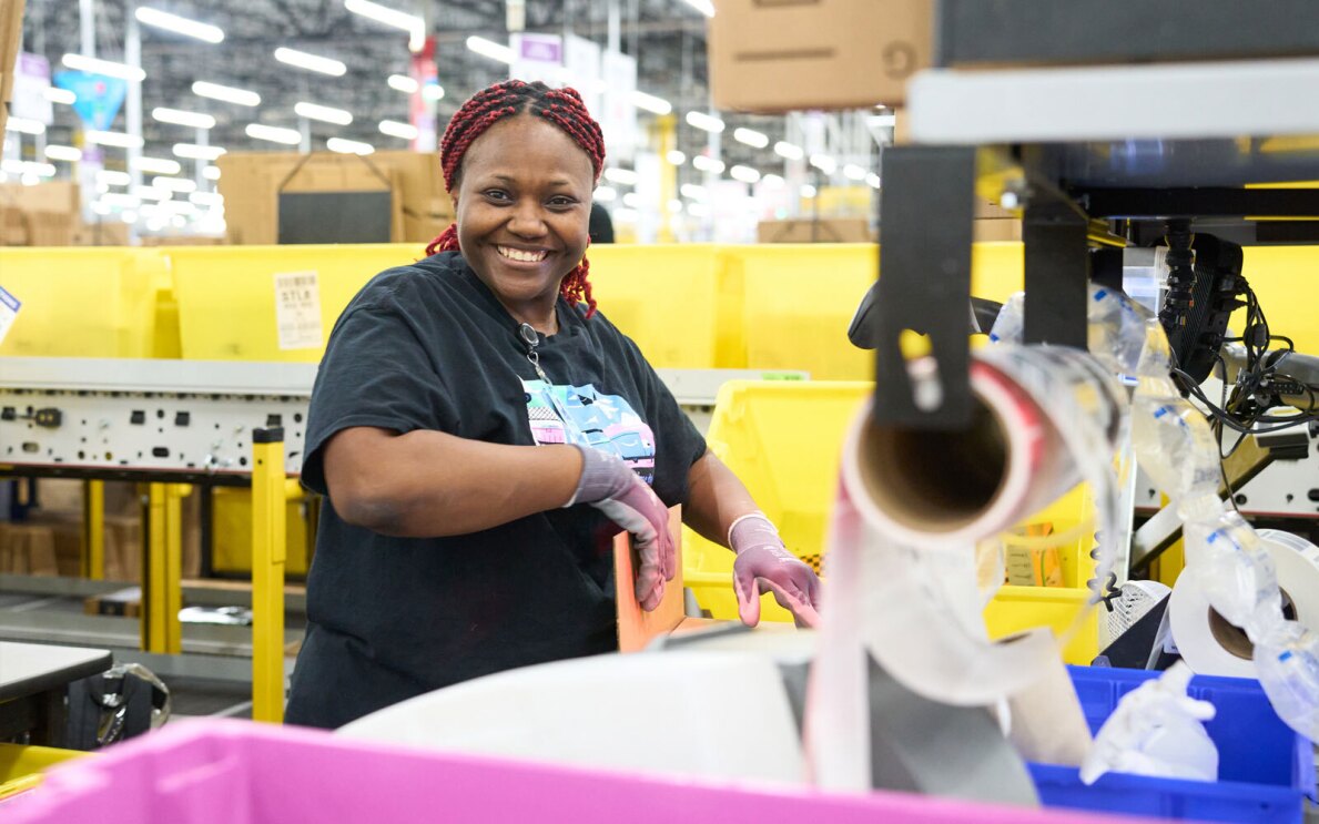 A photo of an Amazon employee sorting packages in a fulfillment center