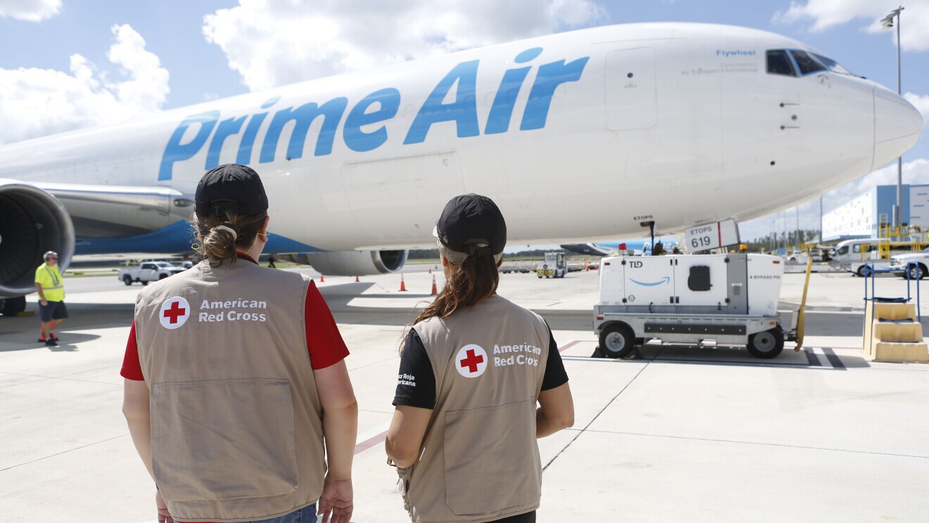 red cross employees in front of a Prime Air airplane carrying humanitarian aid