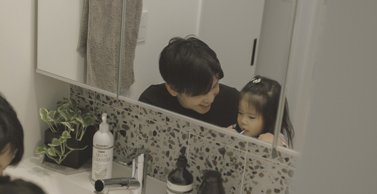 洗面台で子どもの歯磨きを見守るパパさん