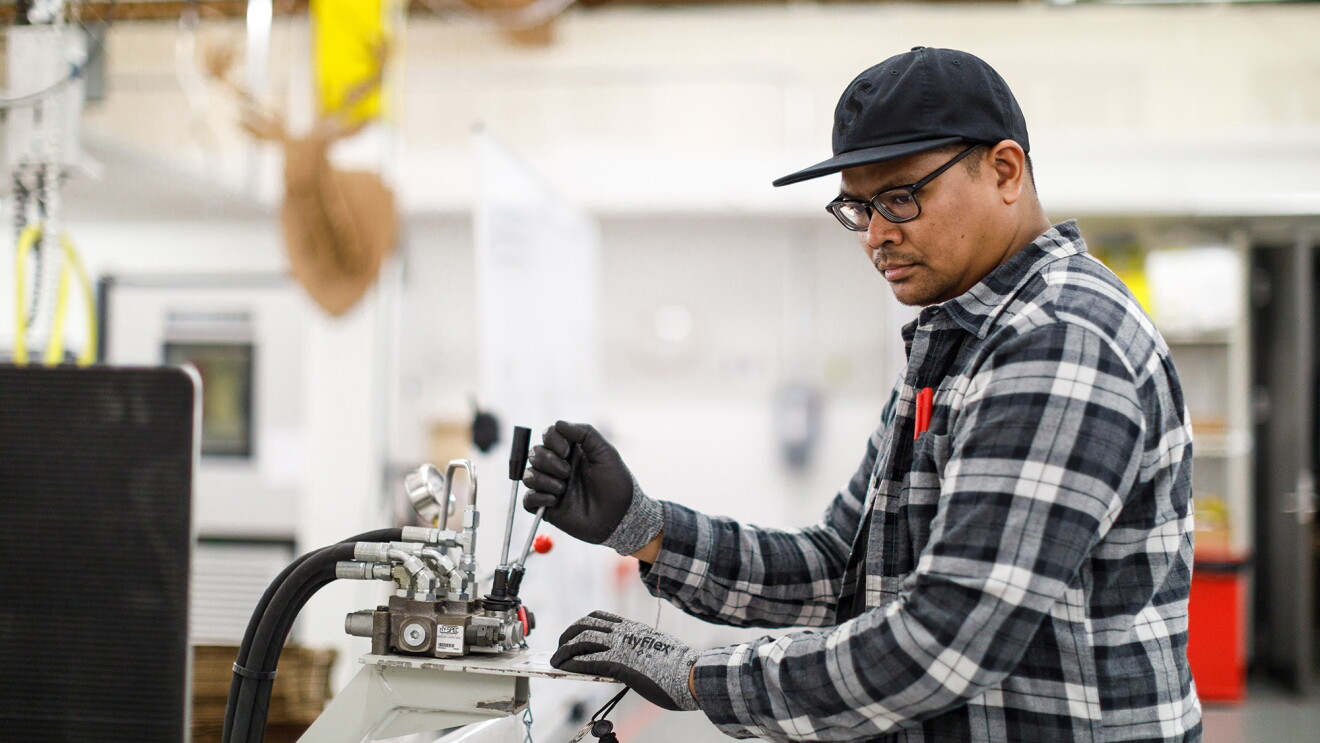 An Amazon packaging lab technician tests the integrity of a cardboard carton on a special machine