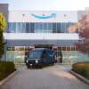 Une image d'une camionnette de livraison Amazon x Rivian devant un entrepôt Amazon