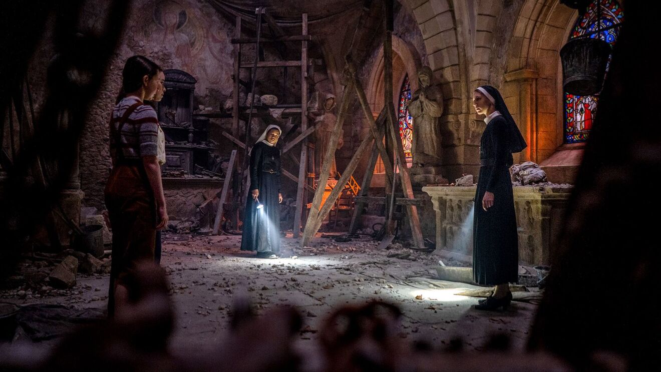 The Conjuring movie: Nuns and civilian explore damaged church interior with flashlights