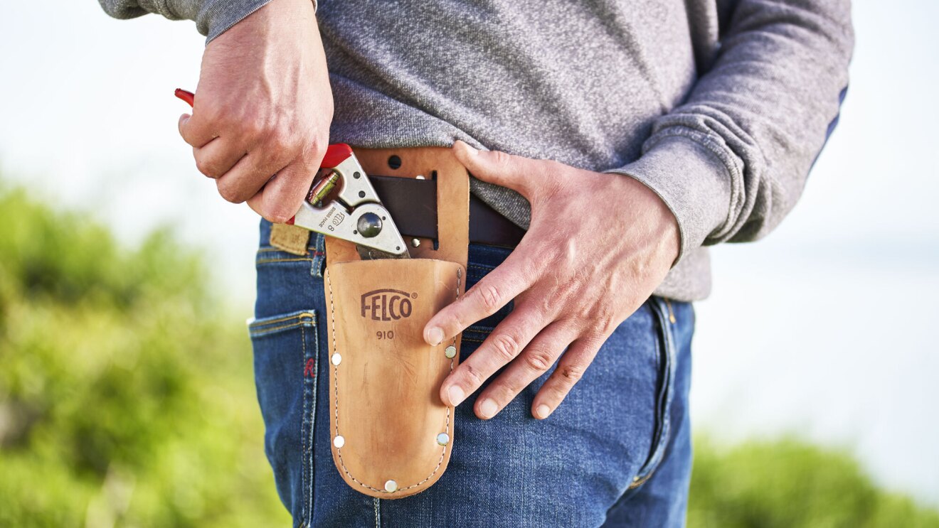 An image of a person wearing a tool belt holder and putting a tool into the holder.