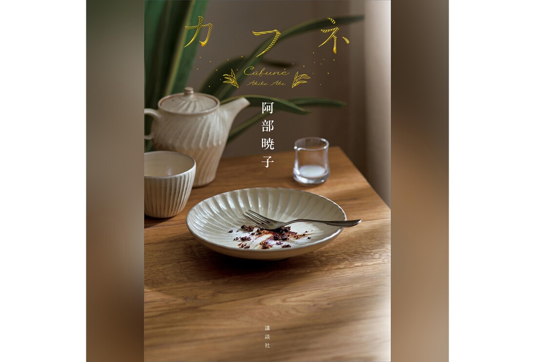 書籍の縦長表紙画像。茶色い木目テーブルの上に、オフホワイトの陶器の皿、ティーポット、カップがのっている。上の方に「カフネ」の黄色い文字。表紙画像左右に同系色のグラデーション背景。