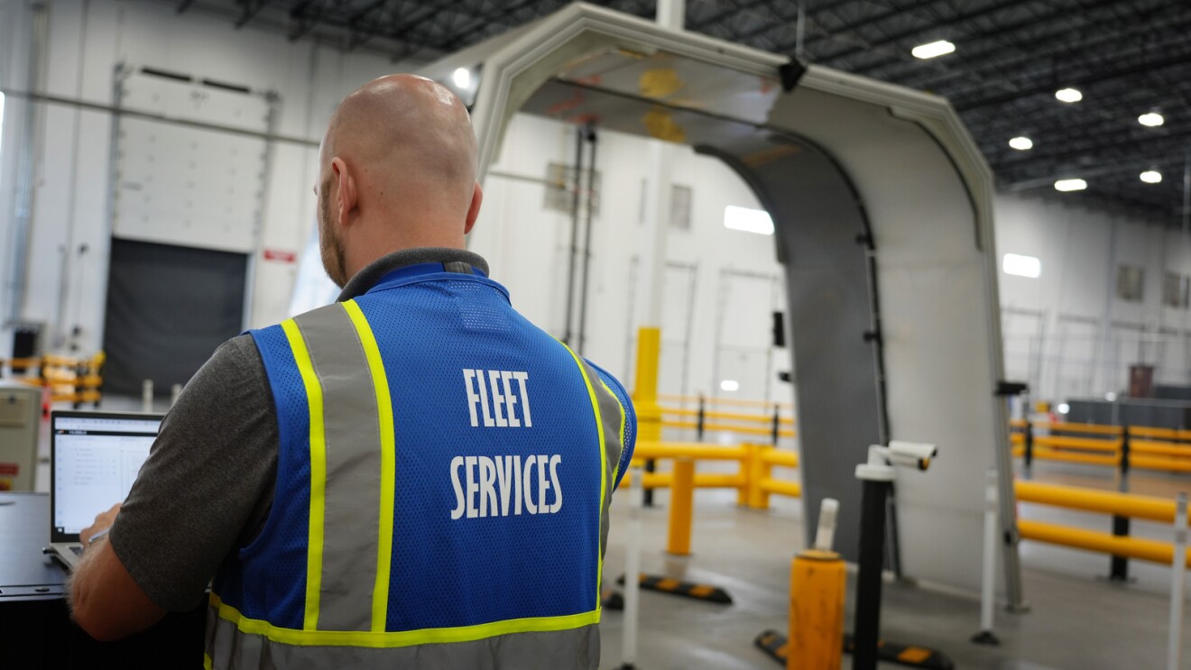 An image of an employee performing an artificial intelligence (AI)–based technology scan on an Amazon delivery van