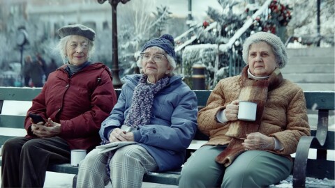 Three elderly women bundled up on bench in winter scene in Amazon Christmas ad