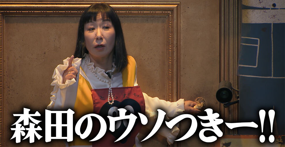 カーキ色の重厚なドアの前に立つ、白い服で赤いゼッケンを着けた人物。右手の人差し指を立て、後ろ手でドアノブを握っている。画面下部に「森田のウソつきー!!」という白い文字のテロップが表示されている。