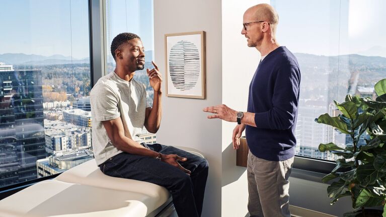 A doctor speaking to a patient in an exam room.