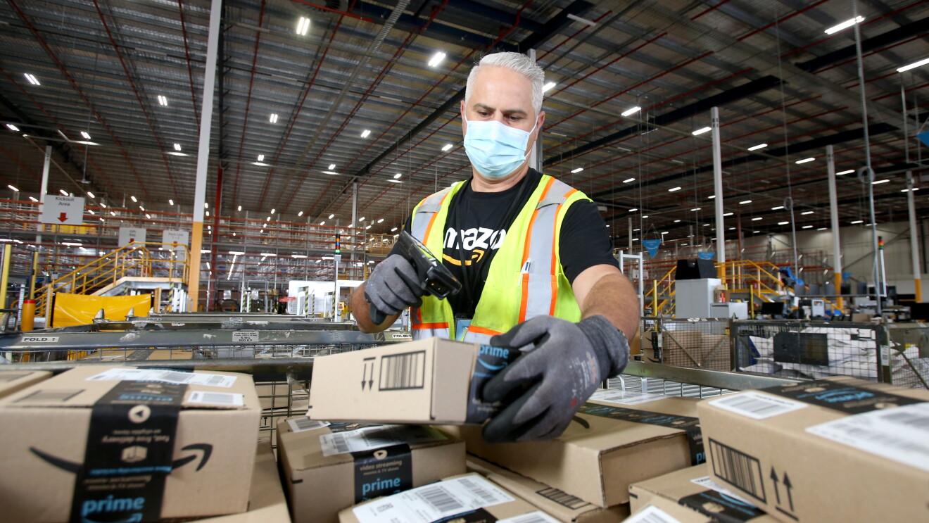 Fil works at Amazon's Brisbane fulfilment centre, scanning parcels about to be shipped to customers
