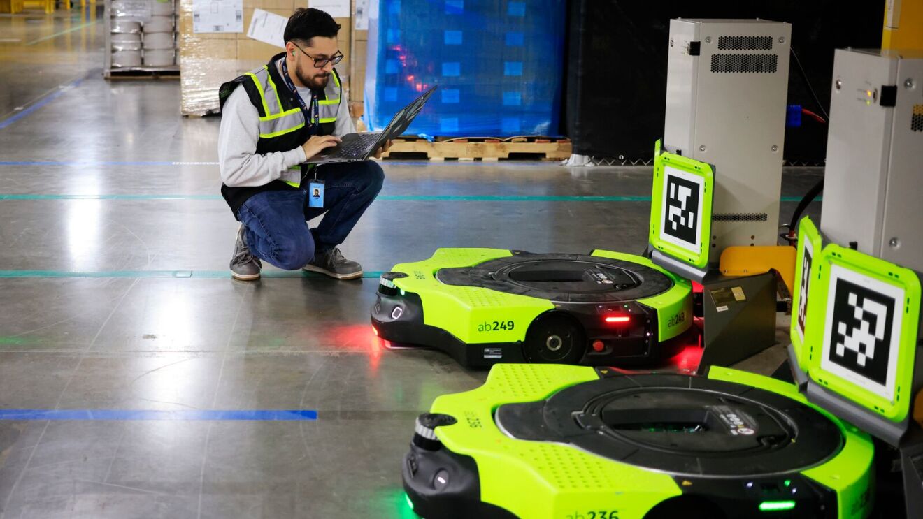 An Amazon employee performing maintenance on a robot