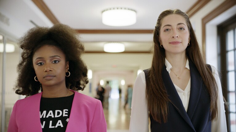 A photo of two people walking through a hallway. 