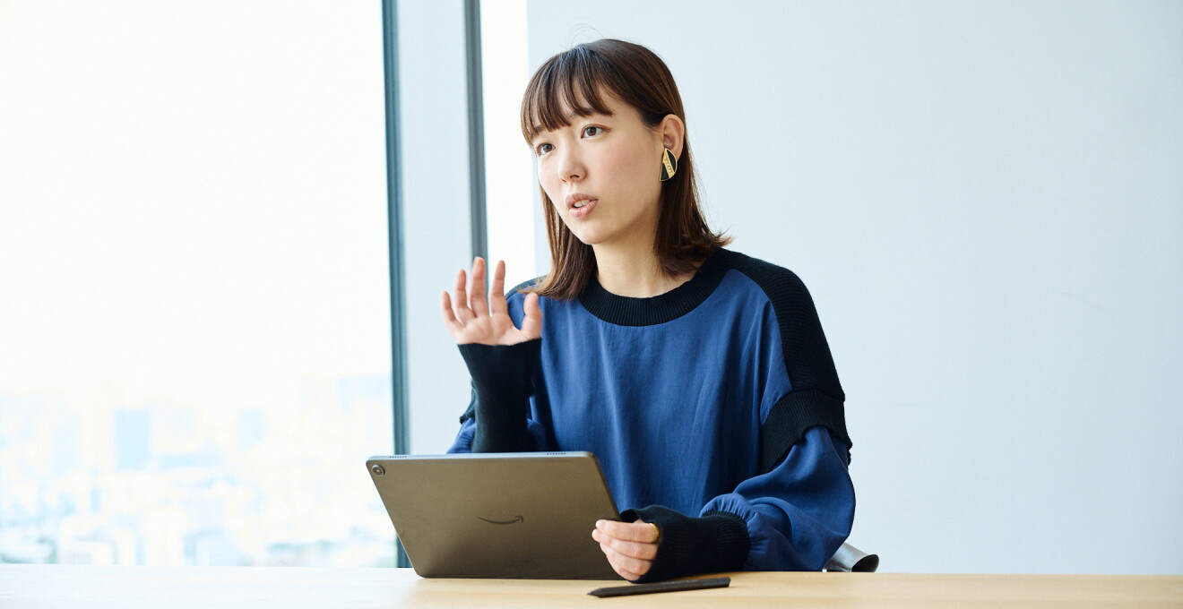 青いカットソーを着たミディアムヘアの女性がタブレットを持っている