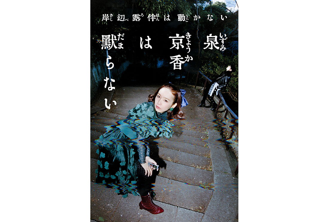 屋外の階段に立つ男女を上から見下ろした構図。手前の女性は手を膝にあてて前かがみの姿勢、奥の男性は手すりにもたれている。