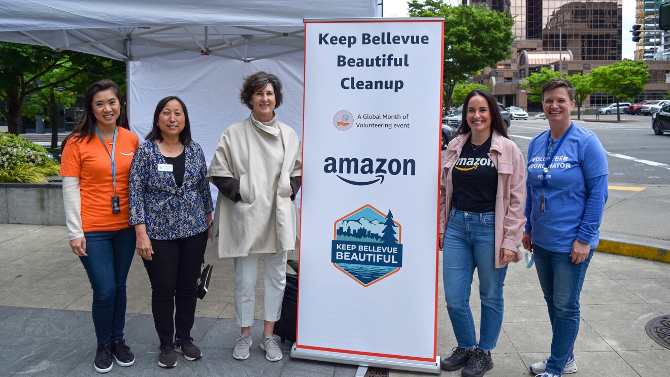 A photo of Mayor Lynne Robinson of Bellevue and Luli Chaluleu, vice president of Talent Acquisition for Worldwide Amazon Stores, and volunteers standing next to a sign that says, "Keep Bellevue Beautiful Cleanup".