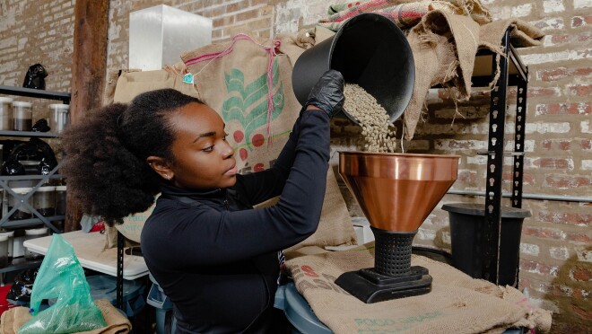 一个咖啡师咖啡豆子倒进一个大咖啡研磨机。